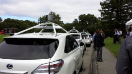 four cars with wireless communications equipment mounted on top and several people standing next to them